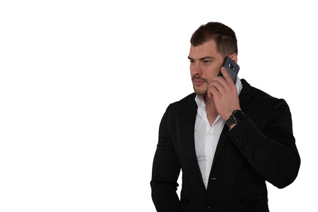 Beautiful serious business man in suit with smartphone on white
