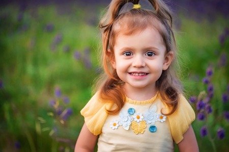 Cute smiling baby girl smiling outdoors in green field. Child portraitの写真素材