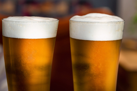 Two glasses of beer on table in restaurant with blurred backgroundの写真素材