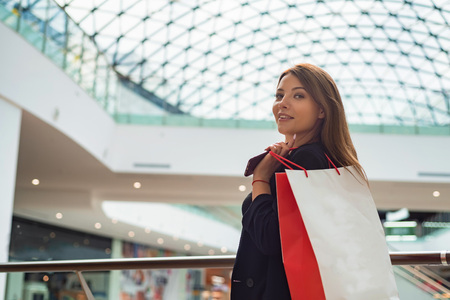 Beatiful dark-haired girl with a shopping bag at the mallの写真素材