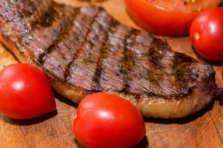 Close up freshly grilled steak on wood with tomatoesの写真素材