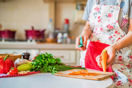 Female hand with peels carrot on wooden board in kitchen. Cooking vegetablesの写真素材