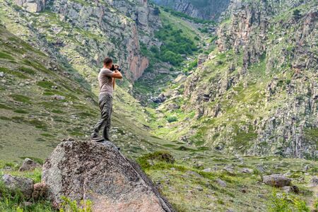 Male hiker takes photo of beautiful mountains in North Caucasus in summerの写真素材