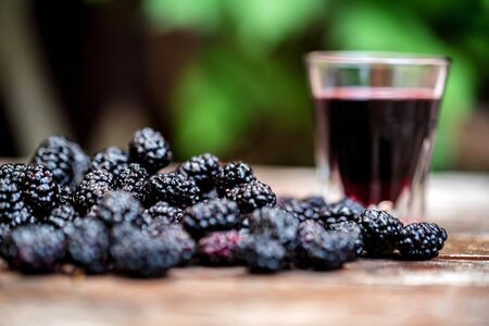 Close up fresh mulberries fruit in bowl and liquor in shotの写真素材