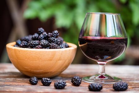 Close up fresh mulberries fruit in bowl and wine in glass