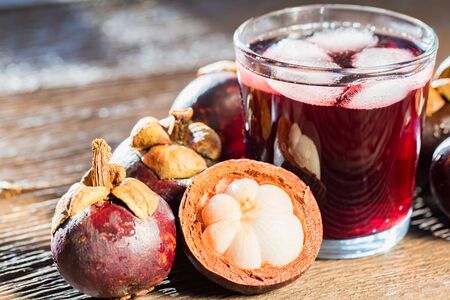Fresh Mangosteen fruit and drink in glass on wooden backgroundの写真素材