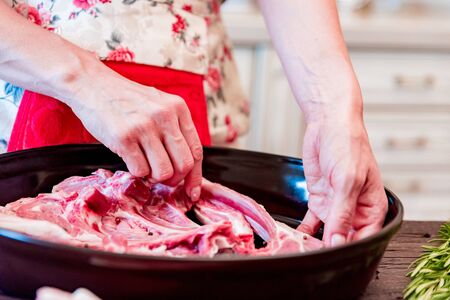 Cook puts raw lamb ribs on frying pan close upの写真素材