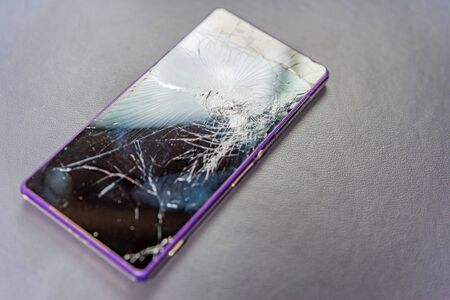 Modern mobile smartphone with purple case and broken screenの写真素材