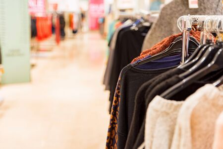 Sweaters hang on rails in modern clothes shopの写真素材