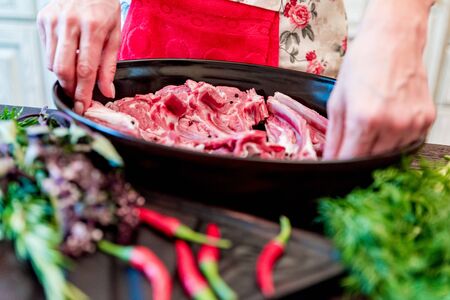 Cook puts raw lamb ribs on frying pan close upの写真素材