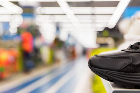 Close view of single sports shoe for sale in sports shop. Defocused background. Sports equipment...