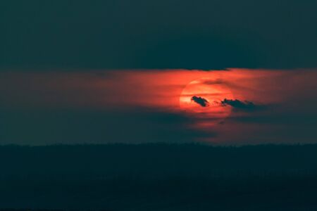 Dramatic sunset sky with dark clouds and red sun