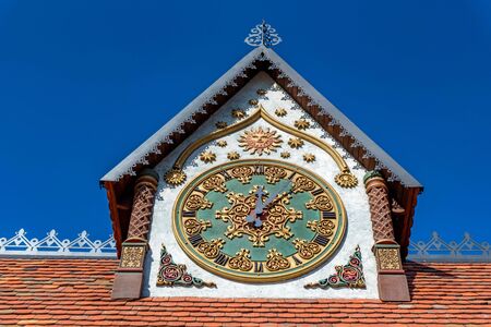 Outside view of decorative clock on tower of a house against blue sky