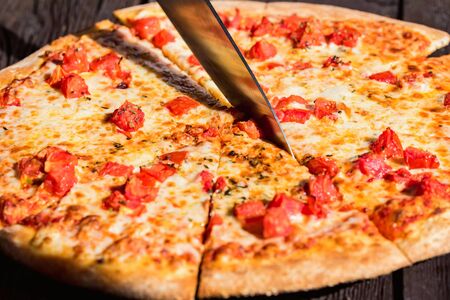 Close up cutting pizza Margherita with tomatoes and cheeseの写真素材