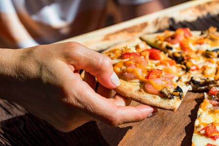 Womans hand taking slice of fresh pizza with shrimps and mushroomsの写真素材