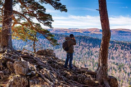 Male hiker takes photo of beautiful mountains in autumn. North Caucasusの写真素材