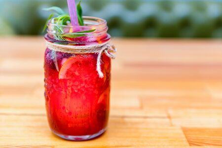A bottle of homemade lemonade or mojito cocktail with lemon, lime and raspberry, cold refreshing drink or beverage with ice. Close-up. Selective focusの写真素材