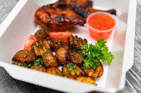 Caramelized BBQ chicken leg quarters with home-made fried potato. Food to goの写真素材