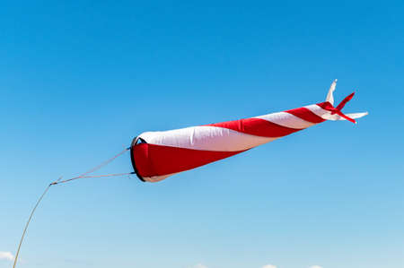 Red and white windsock on a background of blue sky