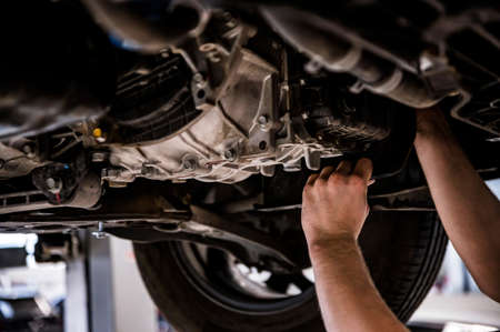 Close up of a mechanic hands repaires lifted carの写真素材