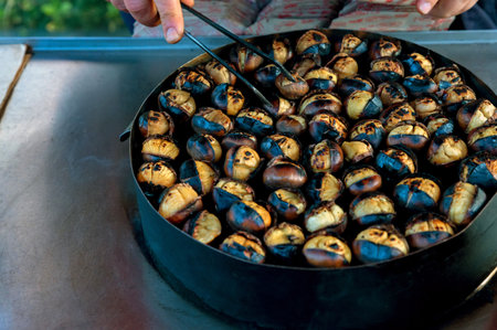 Chestnuts roasting, blacked and bursting open, from a street vendor in autumn.の写真素材