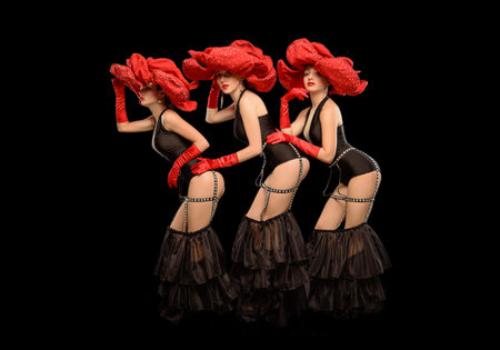 Three beautiful cabaret dancers in red hats isolated on black