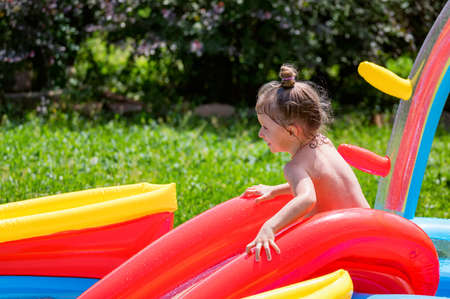 Happy little girl having fun in inflatable swimming pool