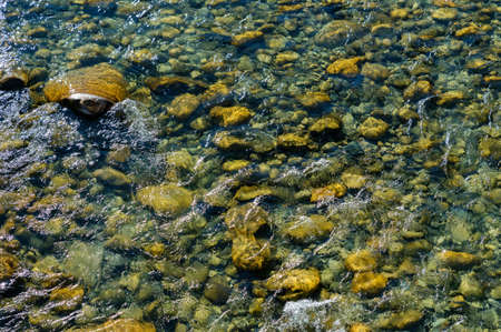 Transparent fresh mountain stream with stones at the bottomの写真素材