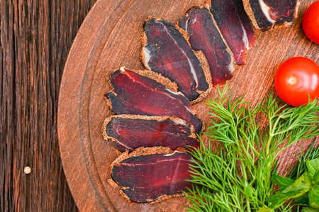 Close up of assorted sliced dry-cured meat on the wooden plate backgroundの写真素材
