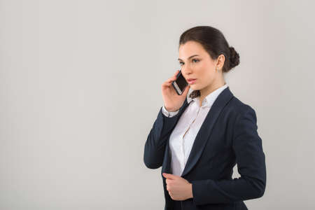 Portrait of serious pretty businesswoman talking on the phone in modern officeの写真素材