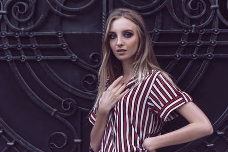 Long-haired young model poses on metal door background