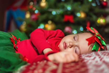 Cute little baby girl sleeping near Christmas treeの写真素材