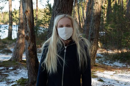 Blonde woman with white face mask, coronavirus, COVID-19, winterの写真素材
