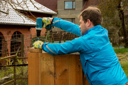 The man makes a wooden box, screw with electric screwdriver, garden jobのeditorial素材