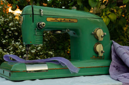 Green old, retro green sewing machine with purple fabric, finger jobの写真素材