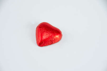 Chocolate candy wrapped in red foil, heart-shaped, food