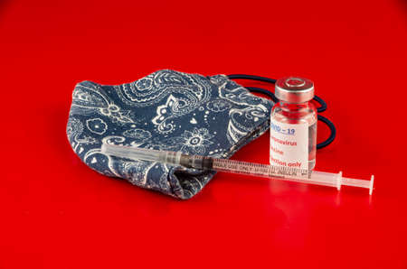 A vaccine with handmade face mask on redの写真素材