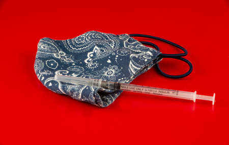 Medical vaccine and handmade face mask on redの写真素材