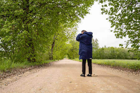 Man in black pants on a blue plait stands on the road, grassの写真素材
