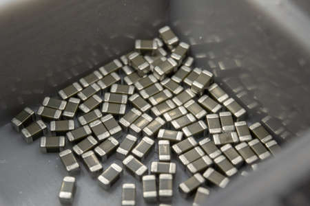 Abstract close-up of 0603 SMT surface mount MLCC capacitors electronics components random scatter in storage containerの写真素材