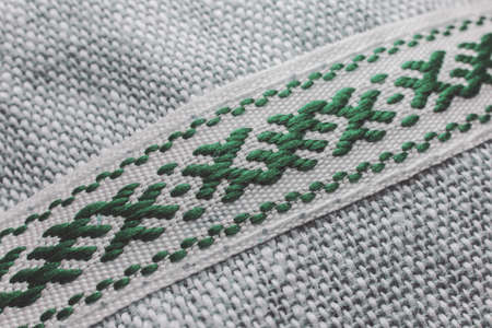 Artistic close-up of traditional symbolic green weave combined white threads on white background in partial focusの写真素材
