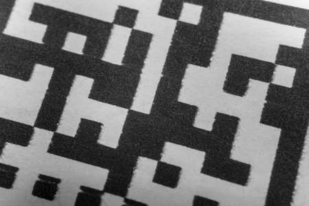 Abstract monochrome close up of isolated printed QR data matrix bar code on white paper label background from material inventory tracking systemの写真素材