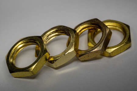 High detail close-up macro of four arranged gold screw nuts isolated on white background in partial focusの写真素材