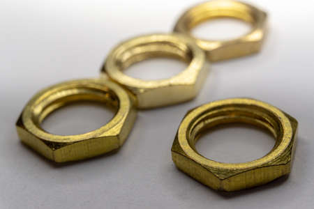 High detail close-up macro of four arranged gold screw nuts isolated on white background in partial focusの写真素材