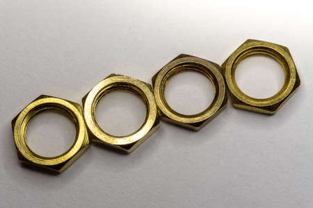 High detail close-up macro of four arranged gold screw nuts isolated on white background in partial focusの写真素材
