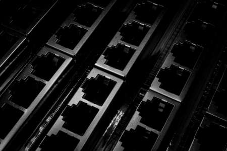 Isolated monochrome close up of closely aligned multiple through hole assembly rj45 networking hardware connectors in partial focusの写真素材