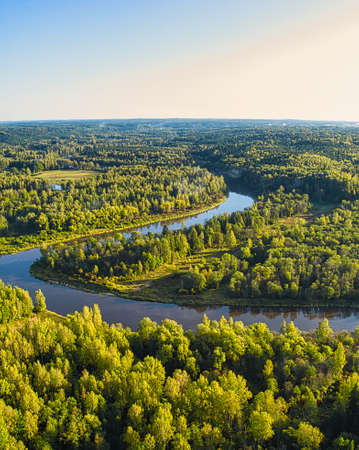Aerial sight of warm, colorful golden autumn morning sunrise mist endless forest covered picturesque river valley curveの写真素材