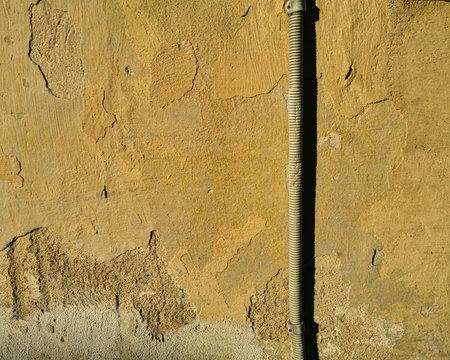 Abstract isolated close-up of brown aged concrete signs of weather and time wear before restoration divided by cableの写真素材