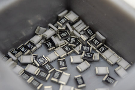 Abstract close-up of grey scattered microscopic 0603 SMT surface mount chip resistors power electronics components sorted in grey container background in random patternの写真素材