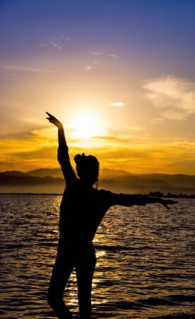 Silhouette.Girl dancing on the beach in the sunsetの写真素材